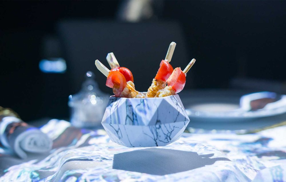 A plated course served under coloured projection light at a 4 Elements dinner show