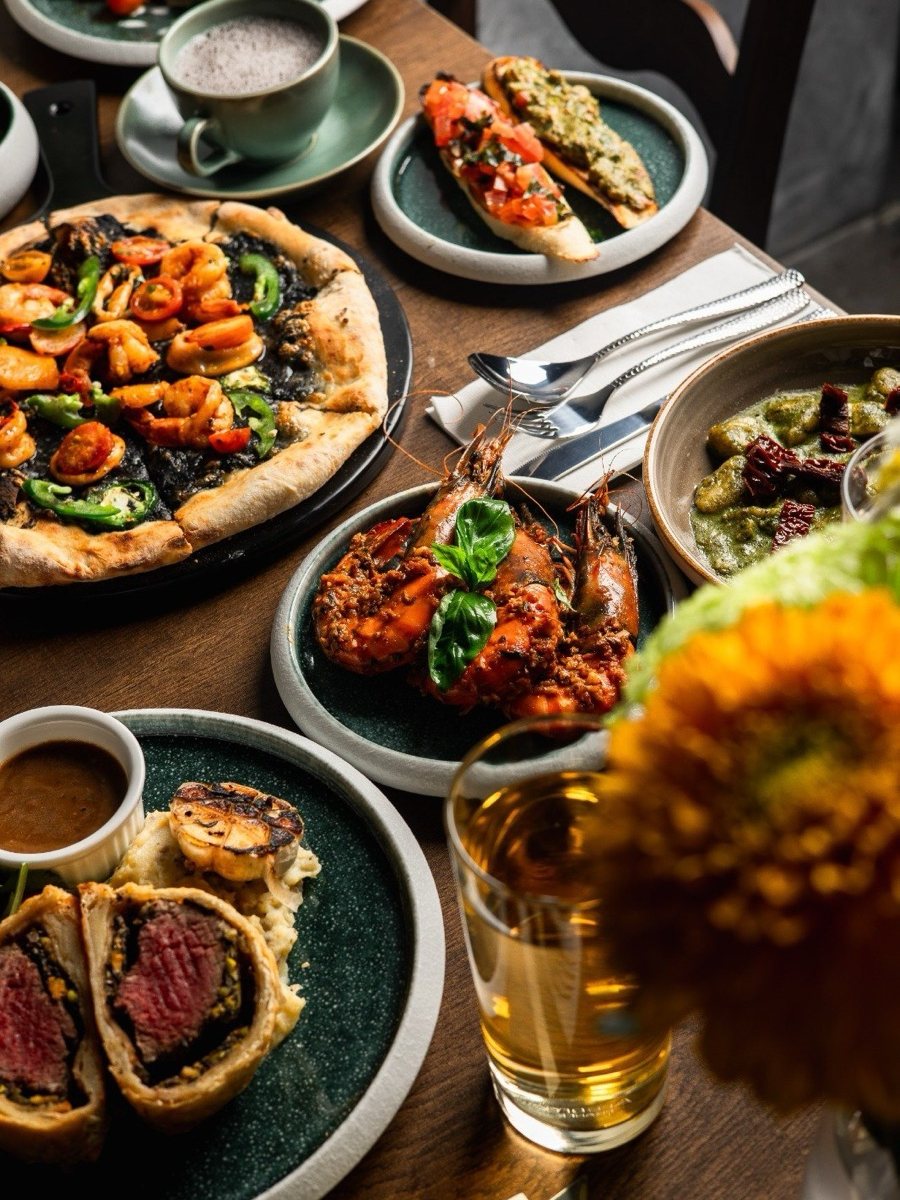 Beef Wellington, prawn pizza and pasta on a table at Epicurean Fusion