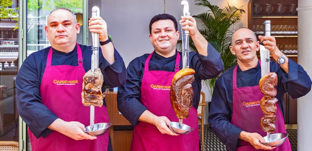 Three Carnivore chefs holding skewers of grilled meat