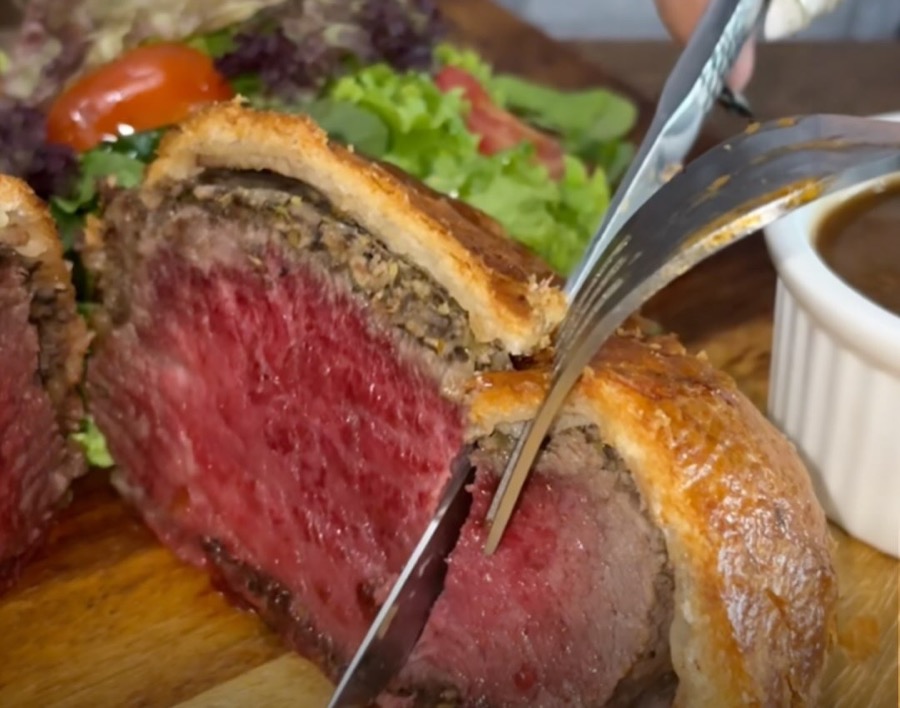 Knife cutting through the beef Wellington at Epicurean Fusion, pink centre and mushroom layer