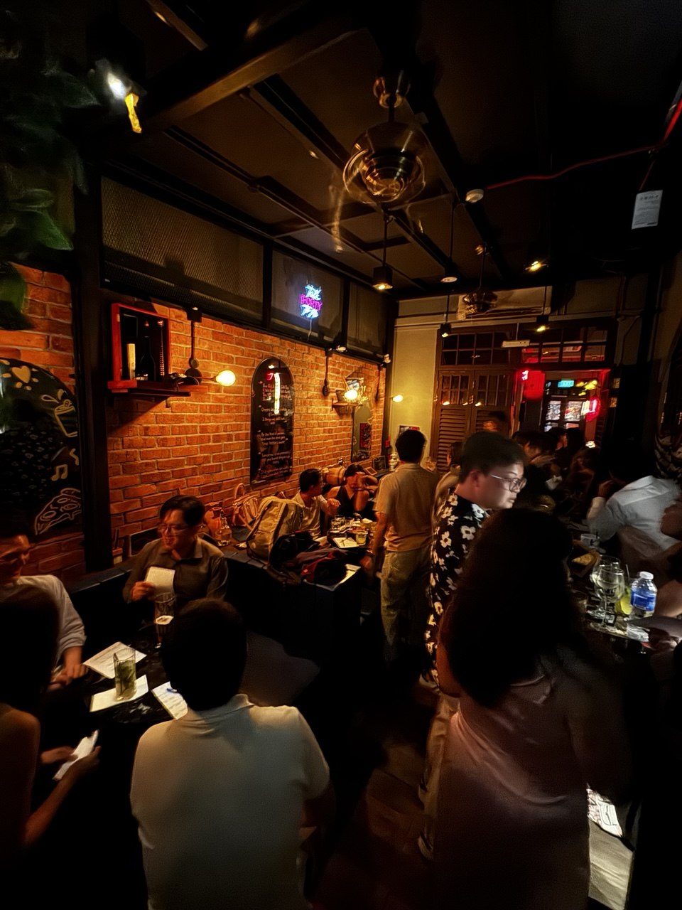 A packed night inside Brooklyn Bar with people standing by the brick walls