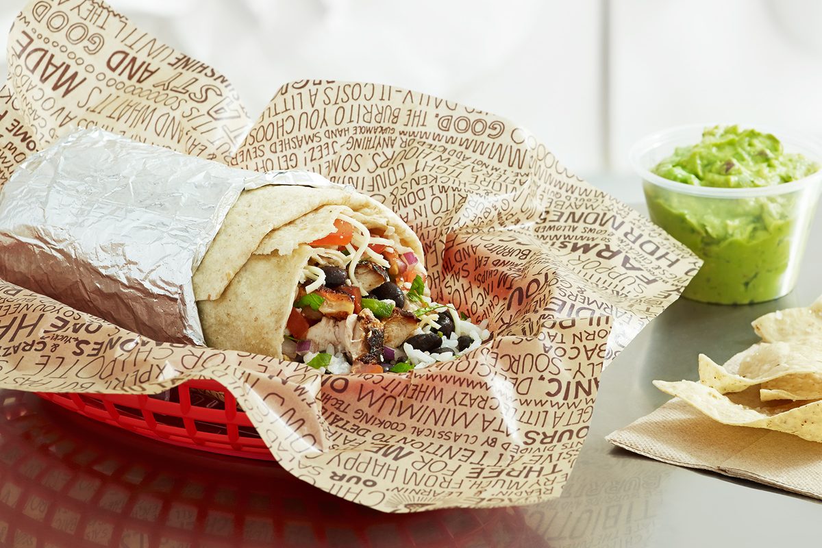 A Chipotle burrito cut open with guacamole and chips