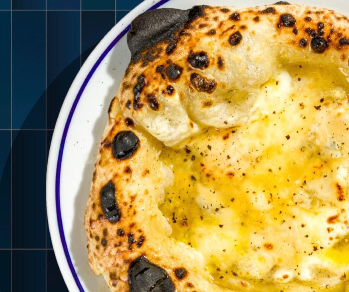 A blistered pizza with melted cheese and black pepper on a blue-rimmed plate at o/sio