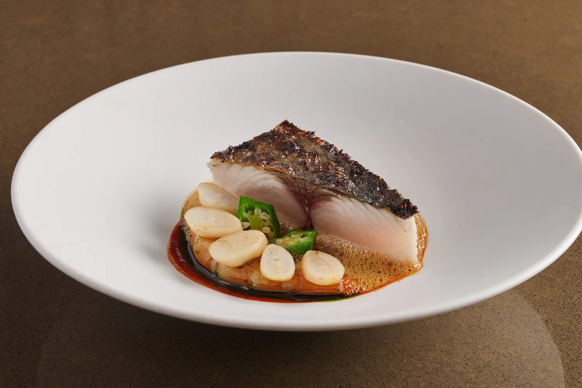 Fish with sauce and scallops on a white plate at Seroja