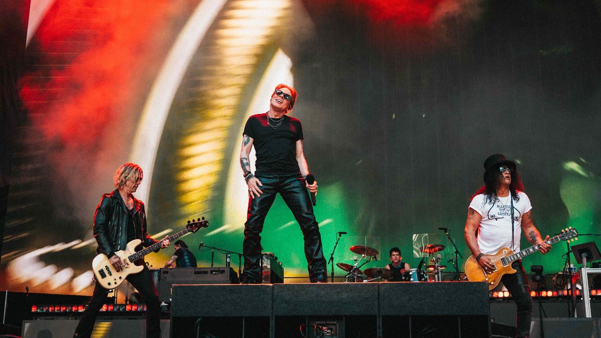 Guns N' Roses performing on a stadium stage with red and green lights