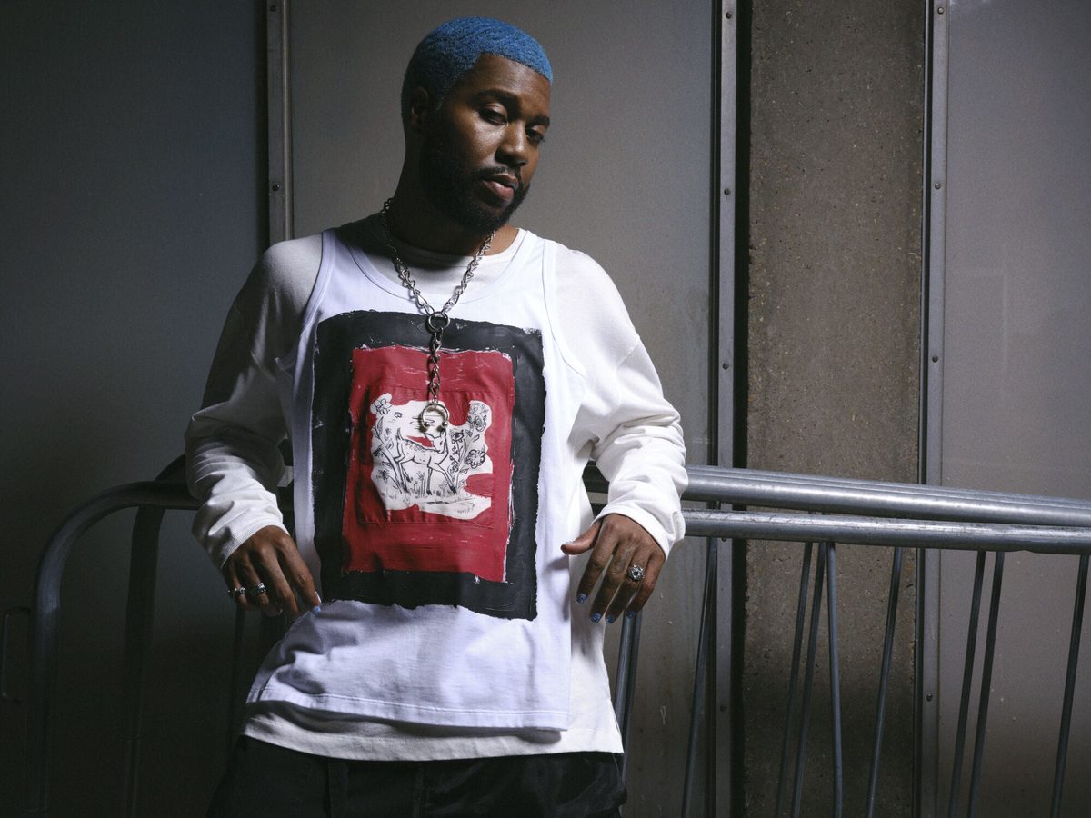 Khalid with blue hair in a white graphic top, press photo