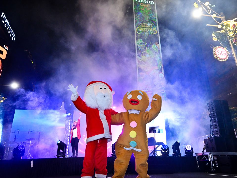 Santa and a gingerbread mascot on stage at Orchard Road's Christmas Eve street party