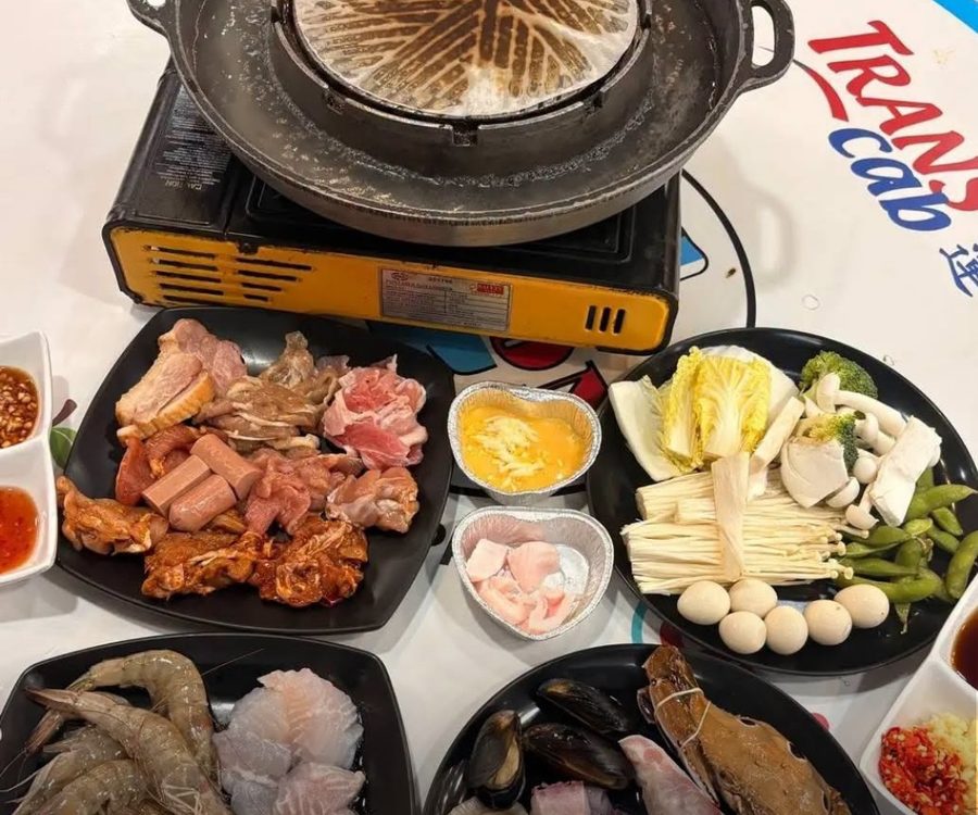A Family Mookata table set with raw meats, live seafood, vegetables and dipping sauces