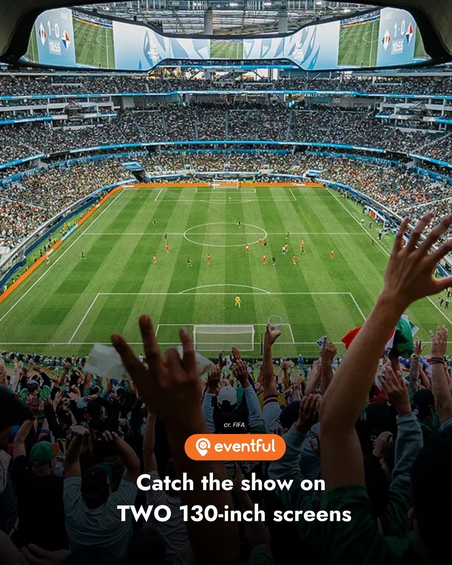 Fans with arms raised watching a match on a giant stadium screen