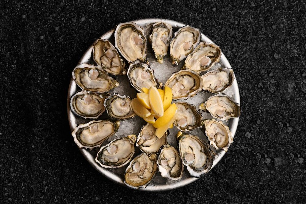 A plate of fresh oysters on ice with lemon wedges at Greenwood Fish Market