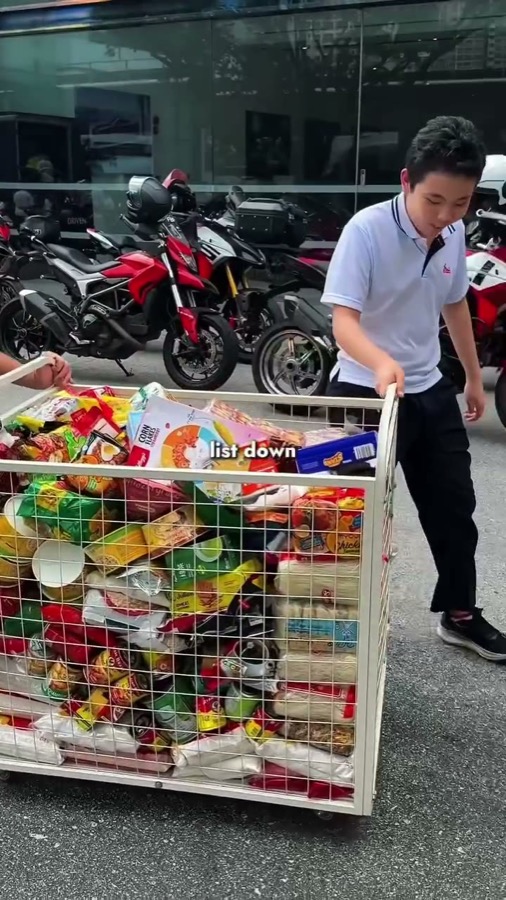 A boy pushes a trolley full of donated instant noodles, cereal and rice at Heart on Wheels 2026