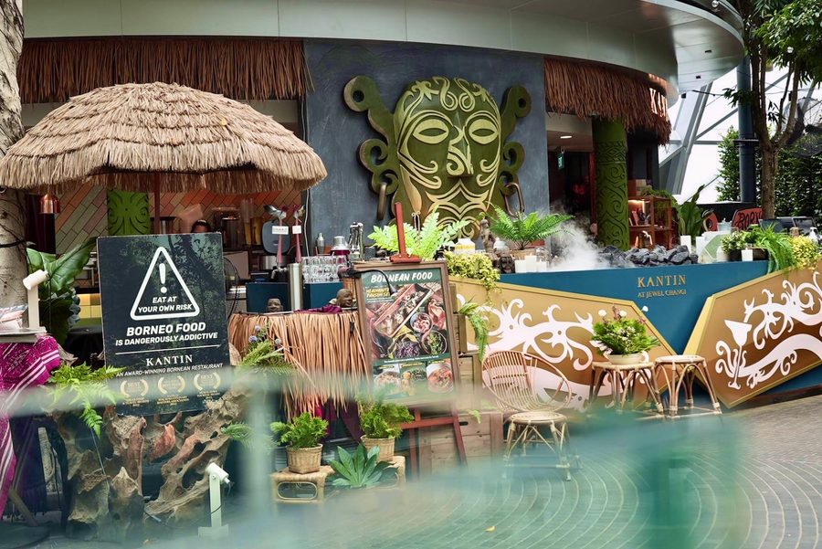 The KANTIN entrance with its carved mask and thatched umbrellas at Jewel