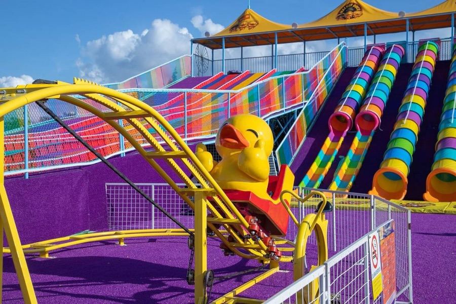 Duck-shaped pedal rollercoaster car in front of rainbow slides at Joyful Dreamland, Johor Bahru