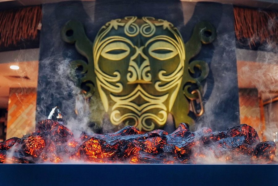The carved mask over the charcoal grill