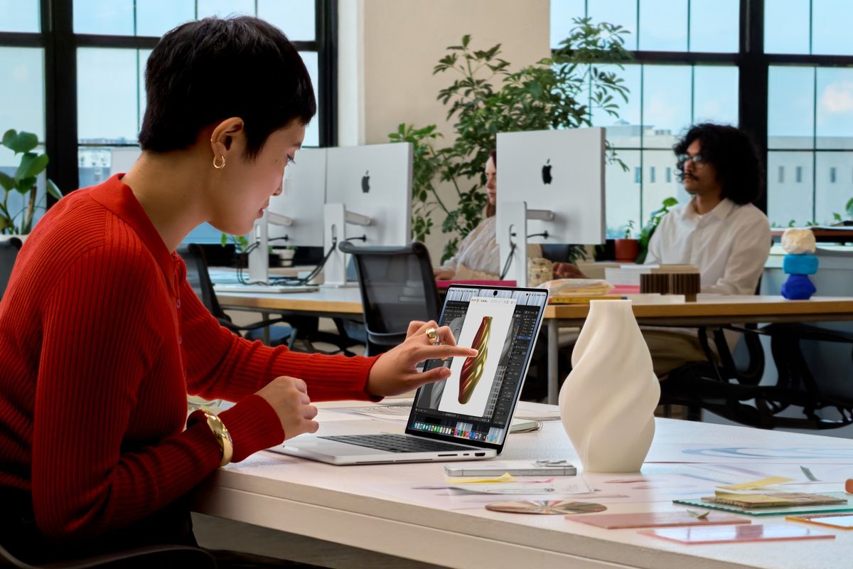 Person tapping the touch screen of a MacBook Pro with PROLED XDR Display at an office desk