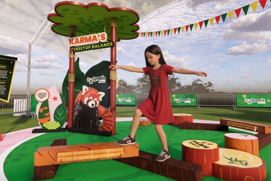 A girl balancing on logs at Karma's Treetop Balance challenge in the Zoolympix Village