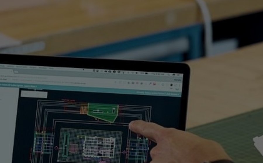 A student pointing at a CAD drawing on a laptop screen in a design studio