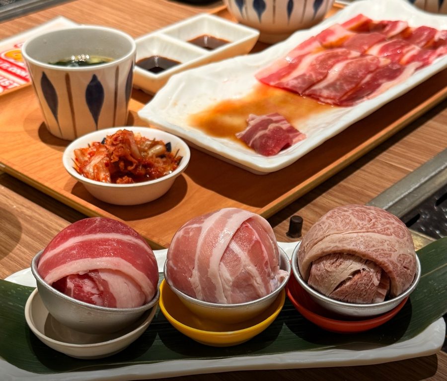 Three raw Yakiniku-GO meat bombs in metal bowls next to a plate of sliced meat