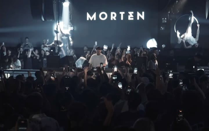 A packed Zouk dance floor under white lasers with an aerialist above the booth