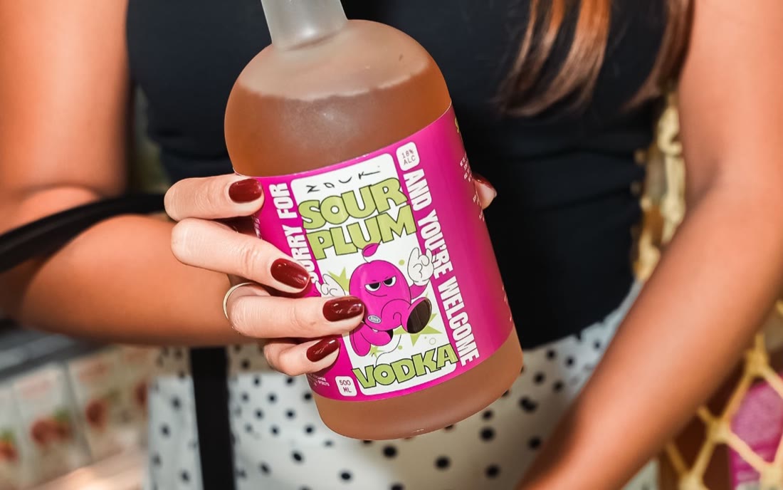 A Sorry For: Sour Plum bottle held up at a night event