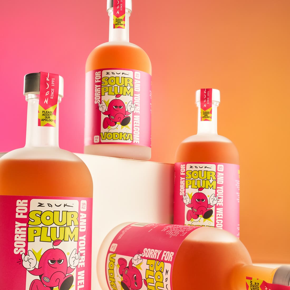 Sorry For: Sour Plum Vodka bottles stacked against a hot pink and orange studio backdrop